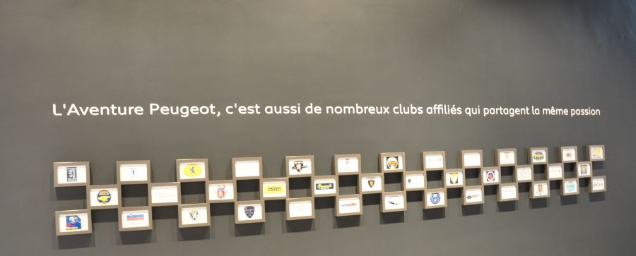 Die "Ehrenwand" mit den Emblemen aller der L'Aventure Peugeot angeschlossenen Clubs im Eingansbereich des Museums. Das Peugeot-Vorkriegs-Register ist in der untersten Reihe als fünfter von rechts zu finden 