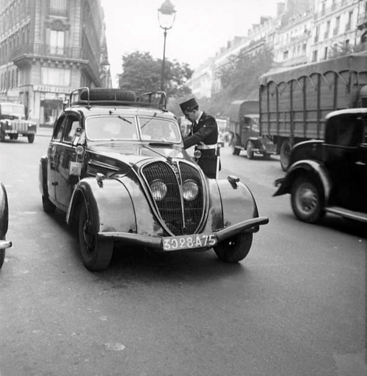1950er. Ein Peugeottaxi vom Typ 402 B wird kontrolliert. Der Taxameter ist links an der Tür zu erkennen.