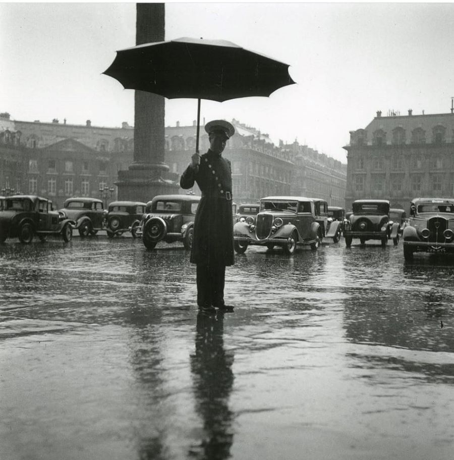 Etwa 1935. Auch in Paris gibt es scheußliches Wetter, dafür hält der Portier des Hotel Ritz einen Schirm bereit. Ganz rechts ein 401 Taxi. 
