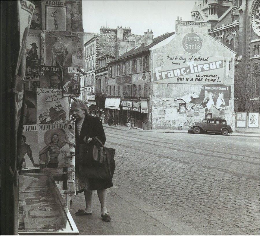 Rue de Menilmontant auf Höhe der Kirche Notre Dame de la Croix Mitte der 1950er. Vor der Werbefassade ein Peugeot 301