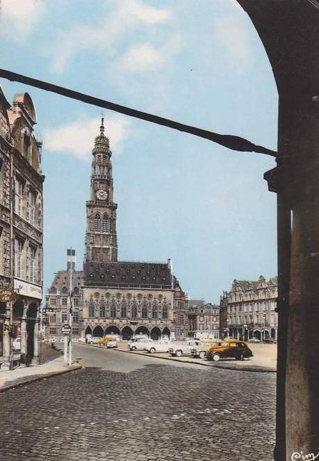 Hier ein coloriertes Bild aus den späten 1950ern. Der Place des Heros, dahinter das Rathaus. Der erste parkende Wagen ist ein Peugeot 202