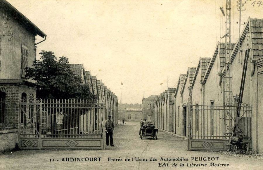 Der Eingang zur Peugeot-Fabrik. Das Foto stammt vermutlich aus dem 1910er Jahren, der Wagen dürfte ein Lion-Peugeot sein. 