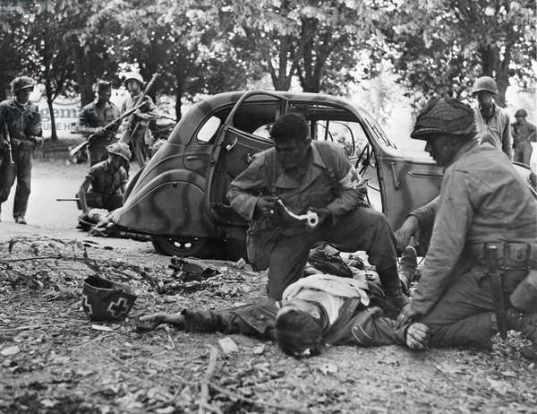 17 August 1944: Nach Kampfhandlungen in der Stadt versorgt ein US-Sanitäter einen verwundeten deutschen Soldaten. 