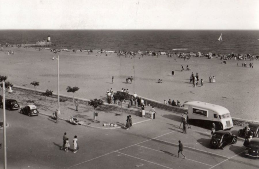 1950er. An der Strandpromenade steht rechts vor dem LKW ein Peugeot 202