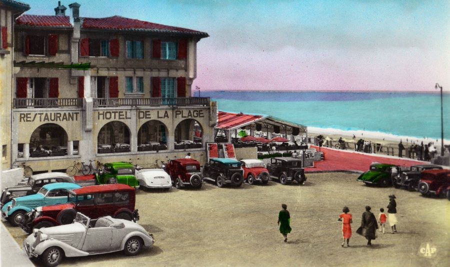 In den 1930ern war das Hotel - wie man an der Parkplatzbelegung sehen kann - wohl ein Luxus-Resort. Der 3. Wagen von links ist eon Peugeot 601 D Coupe (CG9r), der helle unter dem Hotelnamen ein 402 Eclipse. Und rechts erkennt man einen Bugatti. 
Unten das selbe Bild, ziemlich scheußlich coloriert...  