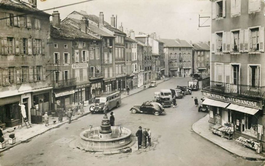 ca. 1950. Auf dem Place du Marechal Foch steht mittig ein Peugeot 302. 
Oben das originale Schwarz-Weiss-Foto, unten eine colorierte Version
